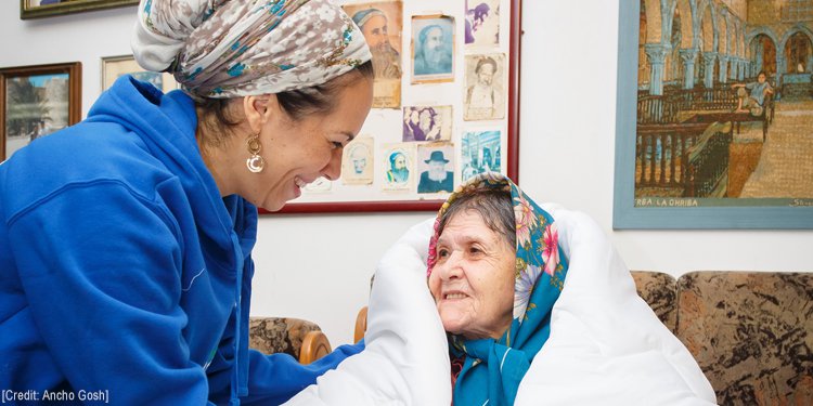 Yael Eckstein smiling at an elderly woman wrapped in a blanket.