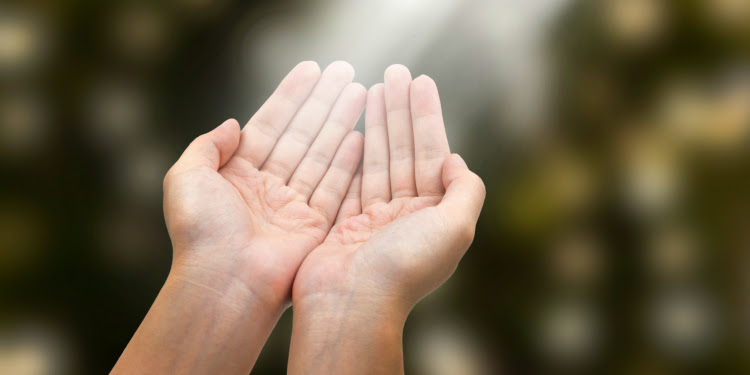 Open hands against a green and brown background.