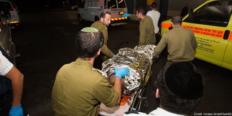 Four men pushing an injured solider on a gurney.