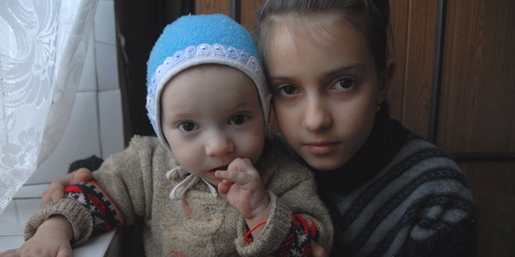Young girl with her baby sister, both whom are orphans.
