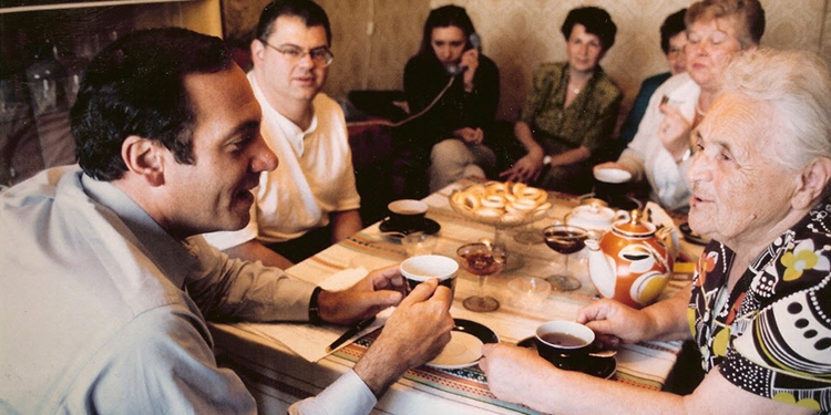 Rabbi Eckstein having tea with several others at a table.
