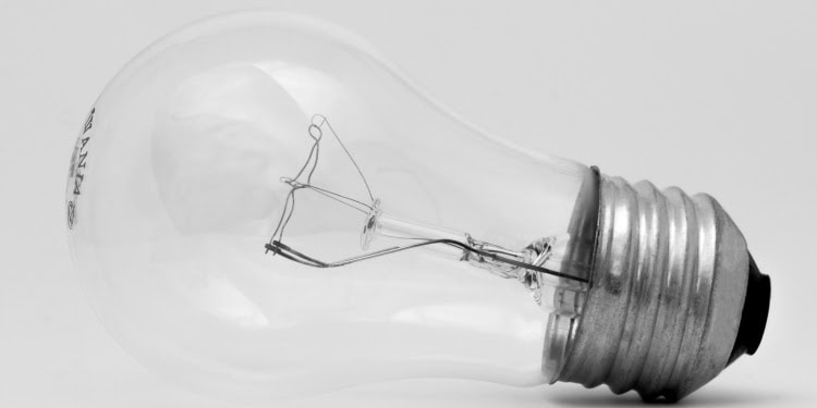 A light bulb laying on a white table against a white background.