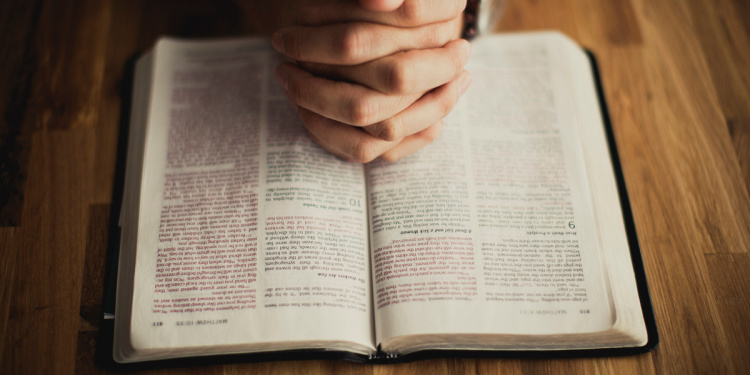 Christians hands praying over Bible