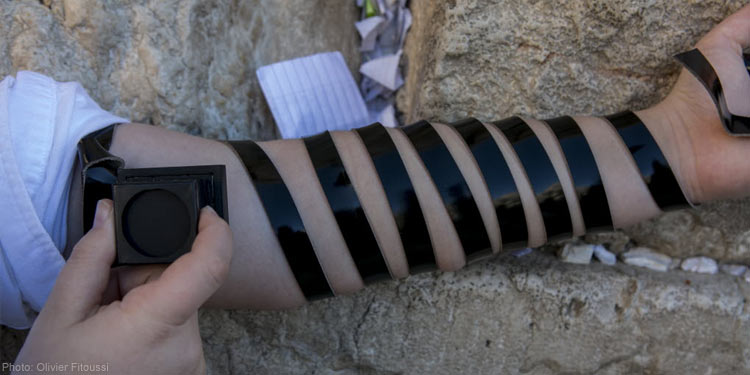 An arm against rocks while black tape is wrapped around the arm.