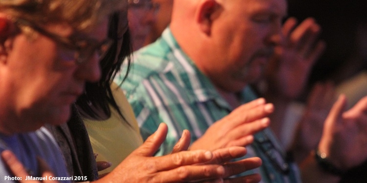 Several people praying together as they raise their hands in praise.