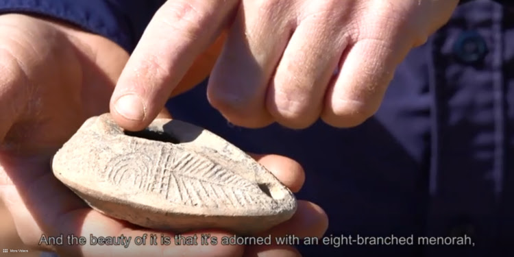 A person pointing at a rare menorah lamp.