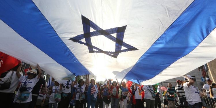 People holding a large Israeli flag during a parade in New York.