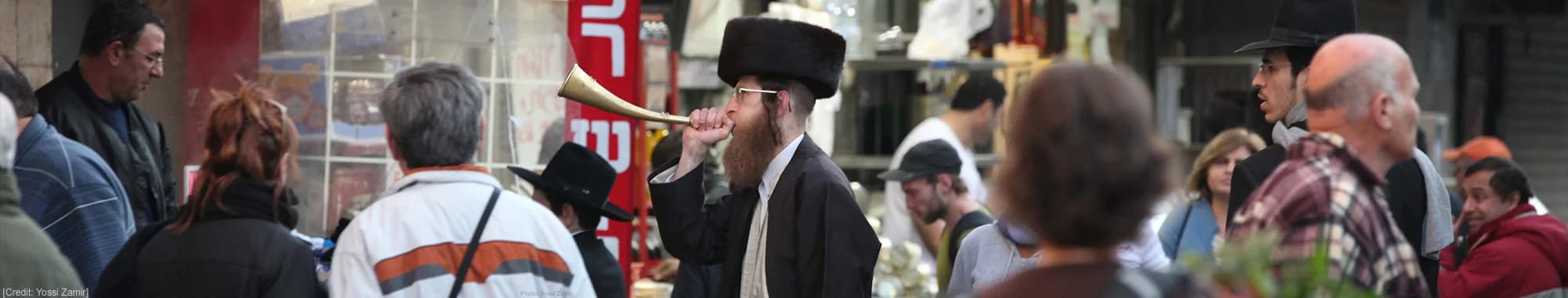 Hasidic Jewish man blowing a golden horn