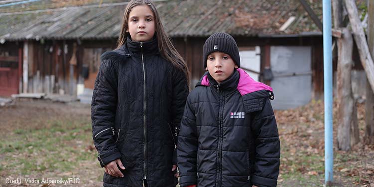 Girl and boy standing side by side outdoors