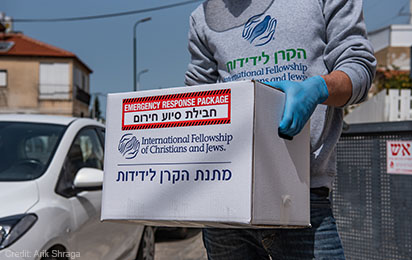 Box labeled "Emergency Response Package" with the IFCJ logo being carried by an unidentified person.