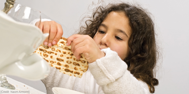 Young girl breaking a piece of bread.