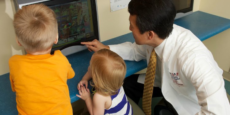 A doctor with two young kids explaining something on a screen.