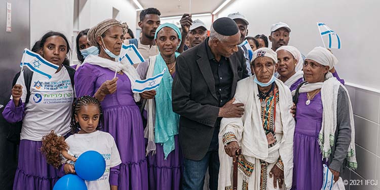 Matriarch of the Ethiopian family - elderly woman, surrounded by men and women holding Israeli's flag