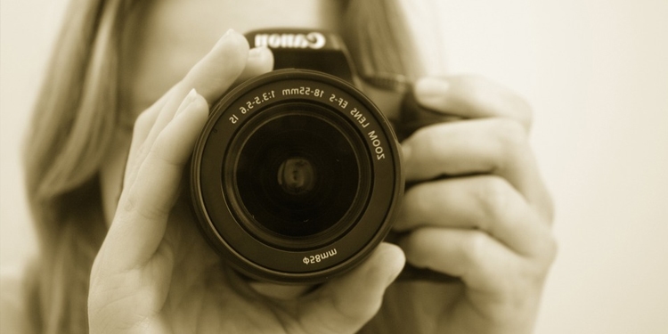 A woman adjusting the lens on a Canon camera.