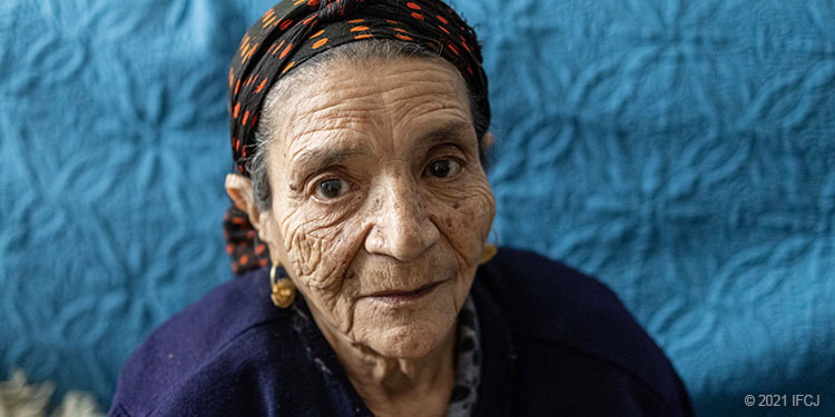 Elderly woman blue sweater, polka dot headscarf, sad, lonely