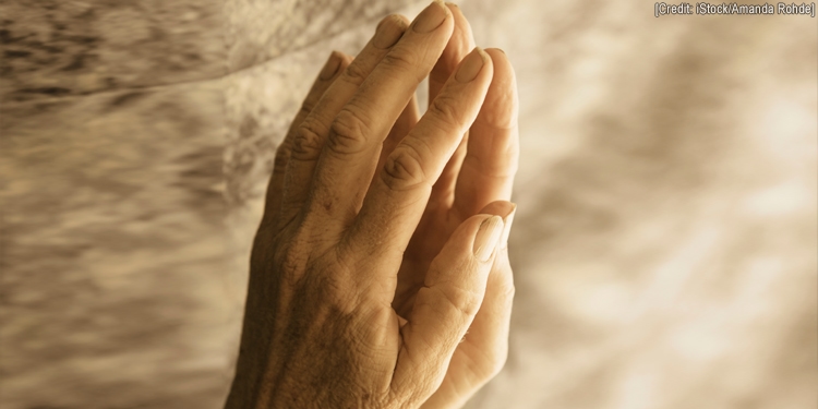 Hands folded together in prayer with a golden background.