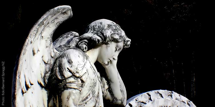 Worn statue of an angel resting his head against his hand