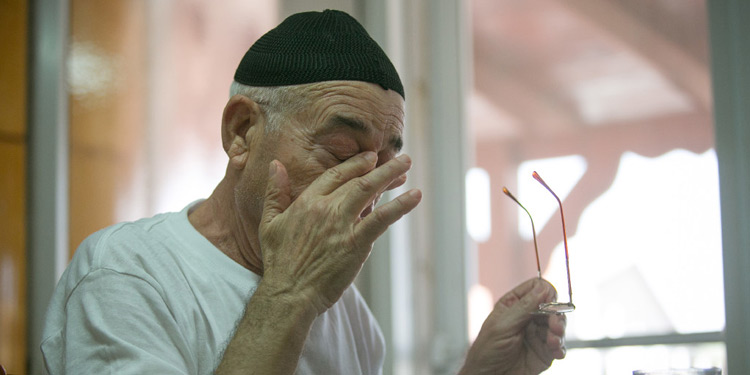 Elderly man wiping his eyes.