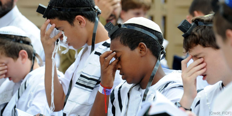 Young boys in white robes praying.