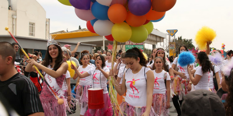 Group of girls in white and pink outfits during a parade for Purim.