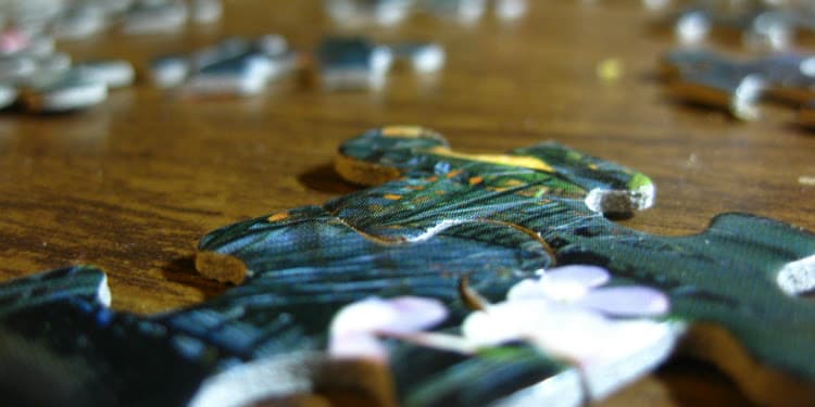 Close up image of a few puzzle pieces together on a wooden table.