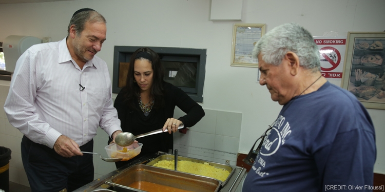 Rabbi and Yael Eckstein serving food to an elderly Jewish man.
