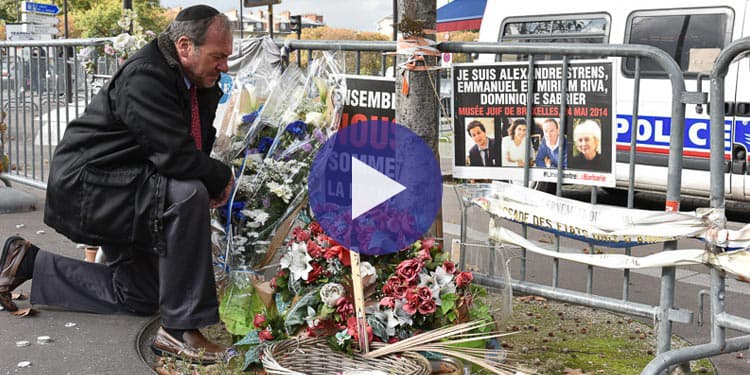 Rabbi Eckstein kneeling near a memorial with flowers and praying.