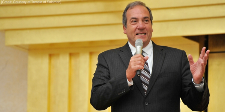 Rabbi Eckstein giving a talk to a crowd with a microphone in his hand.