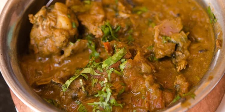 A metal pot filled with curry chicken and vegetables