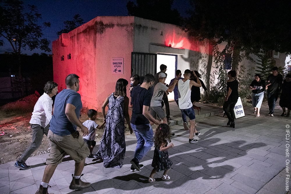 Several people running to a bomb shelter while under red alert.