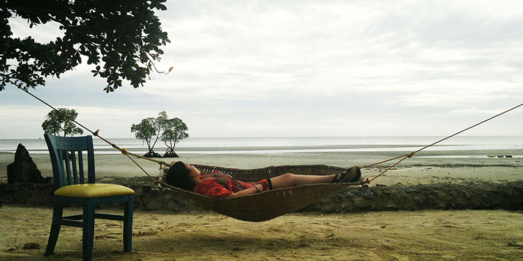 Woman lying on a hammock on the beach.