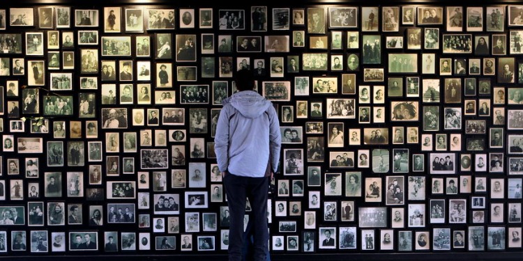 Man looking at several pictures of those who passed in the Holocaust.