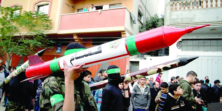 Group of soldiers walking down a street while holding rockets.