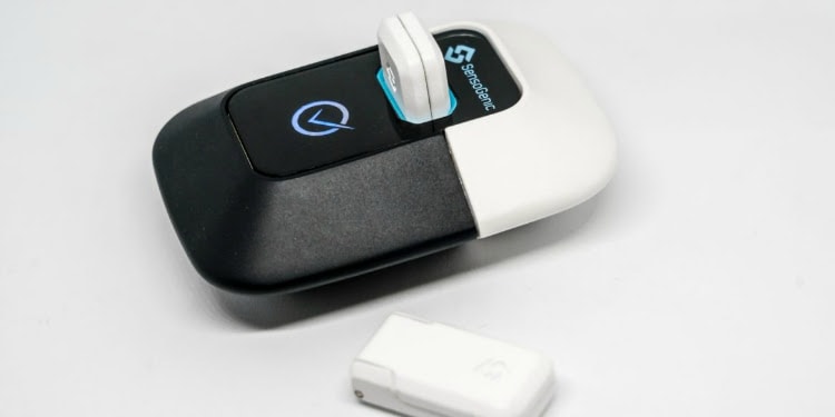 A sensor gadget with two additional accessory pieces against a white background.