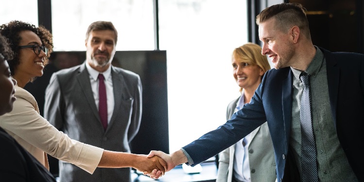 Two people shaking hands in a board room.