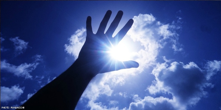 Hand waving in the air with a cloudy blue sky behind it.