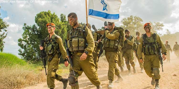 Israeli soldiers marching in the sun while carrying the flag of Israel