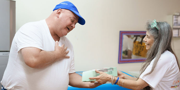 Soup kitchen volunteer giving light green box to adult man