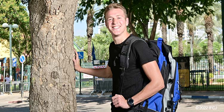 Young adult man stand by tree