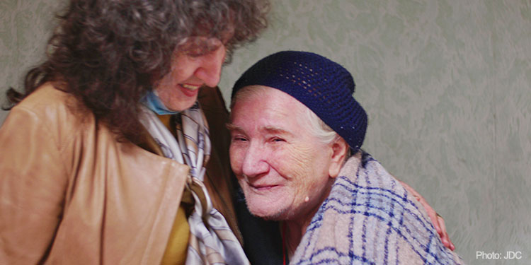 Elderly woman living in Georgia, hugging employee of JDC