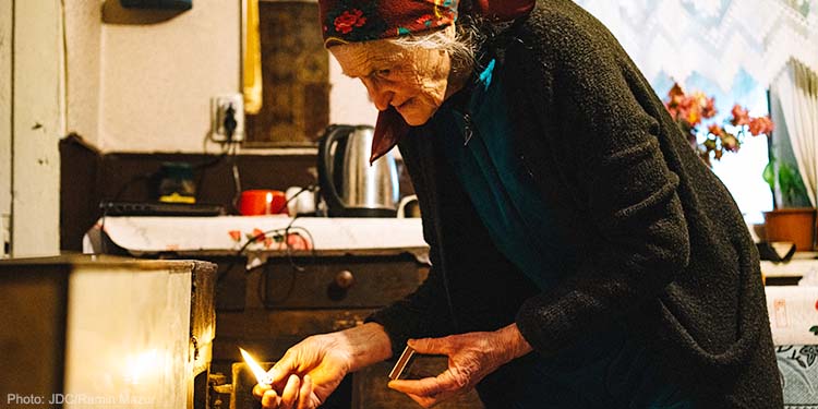 Elderly woman lights fire in stove