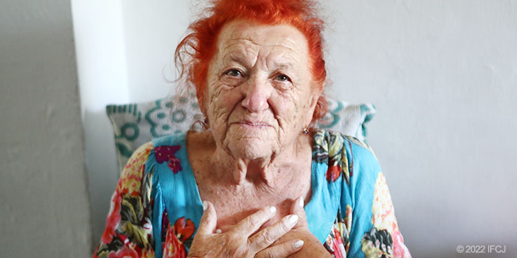 Elderly woman sit with hands crossed on her chest