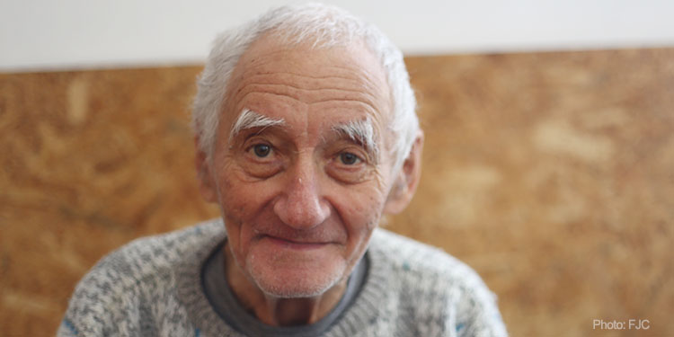 Elderly man, Holocaust survivor sitting looking at camera