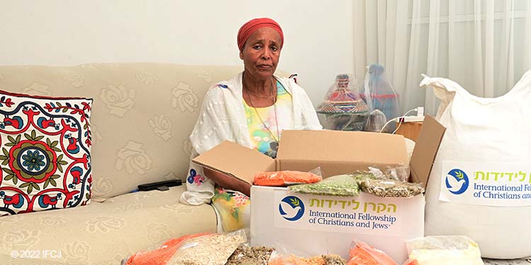 Elderly Ethiopian woman sitting on couch next to table and food box