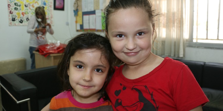 Two young girls in red shirts smiling at their after school program.