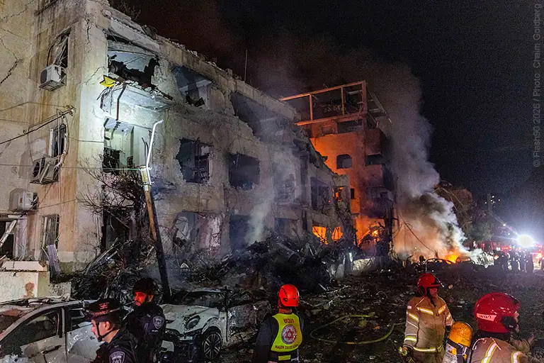 Emergency responders battling a large fire at a multi-story building. Flames and smoke billow from the structure as firefighters work to control the blaze and ensure safety.