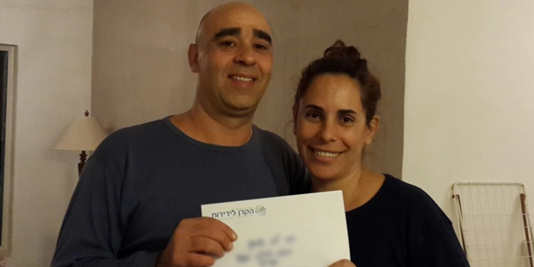 Terror survivors holding a piece of paper together while smiling at the camera.