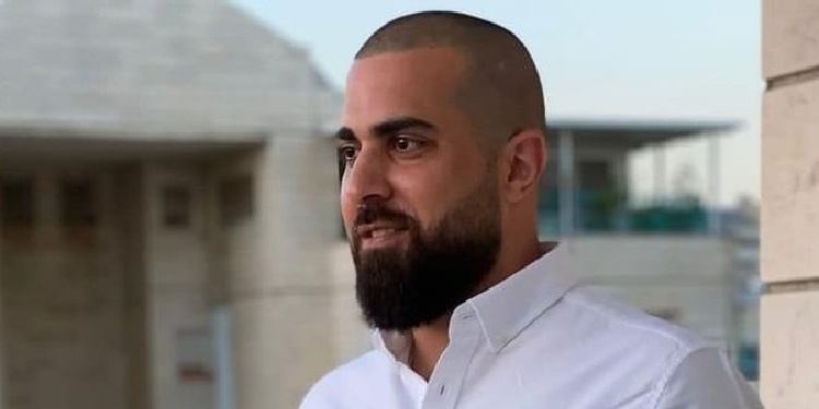 Man in a white button up shirt looking off into the distance smiling.