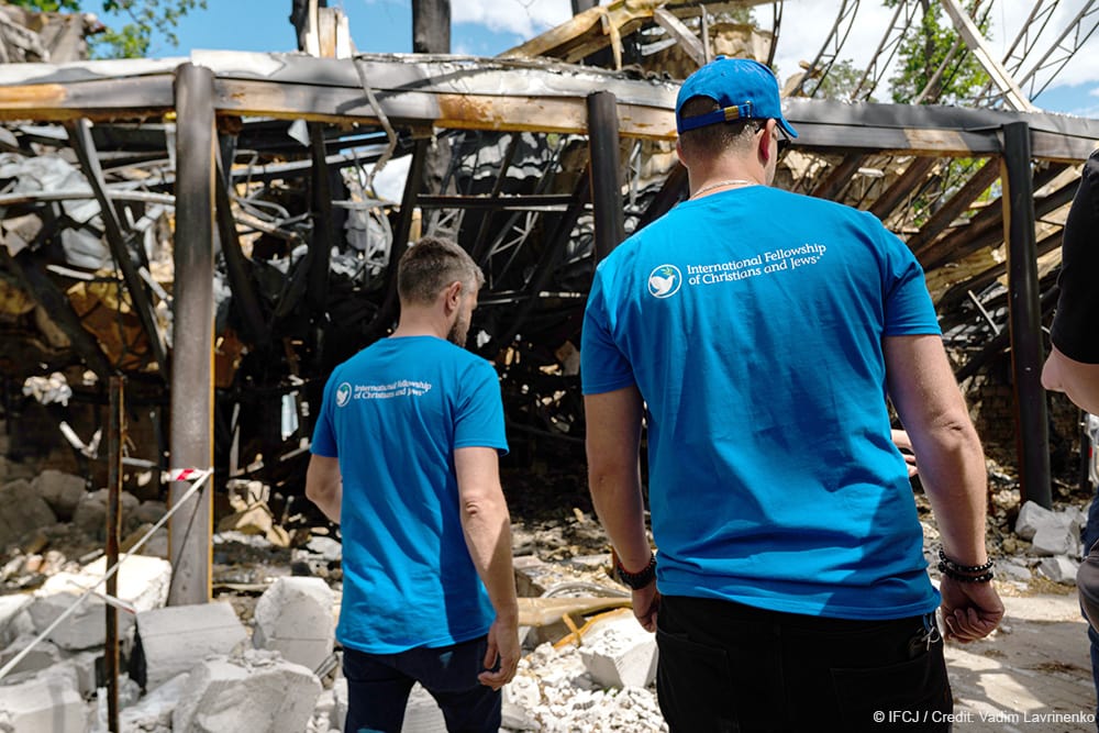 2 men standing near the remains of a building destroyed in Ukraine