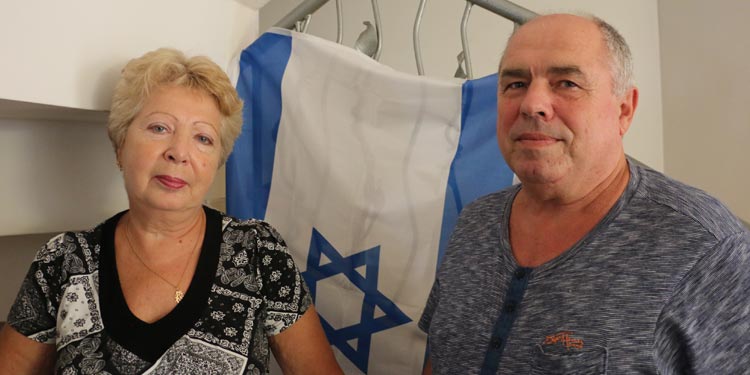 Couple looking into the camera with an Israeli flag behind them.